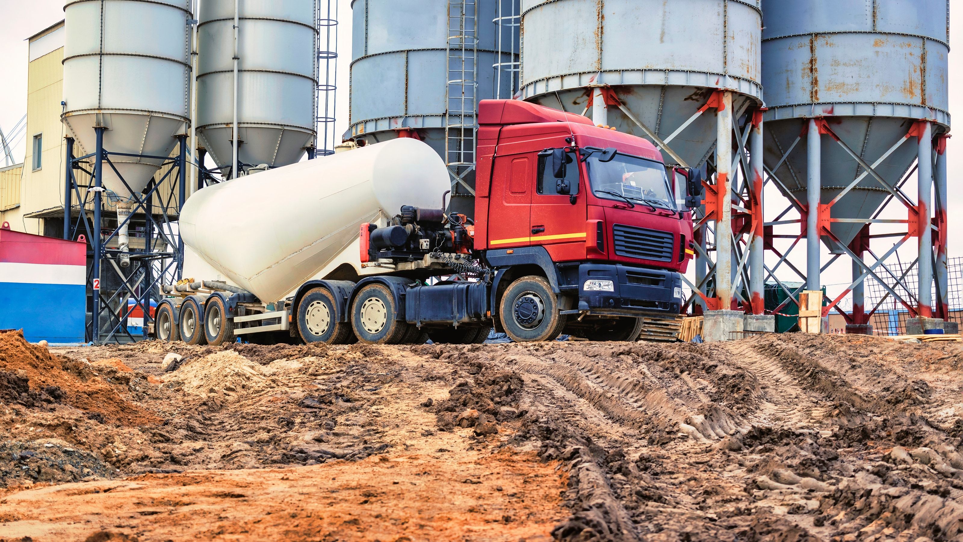 Cisterna de cemento descargando junto a los silos de una planta de hormigón