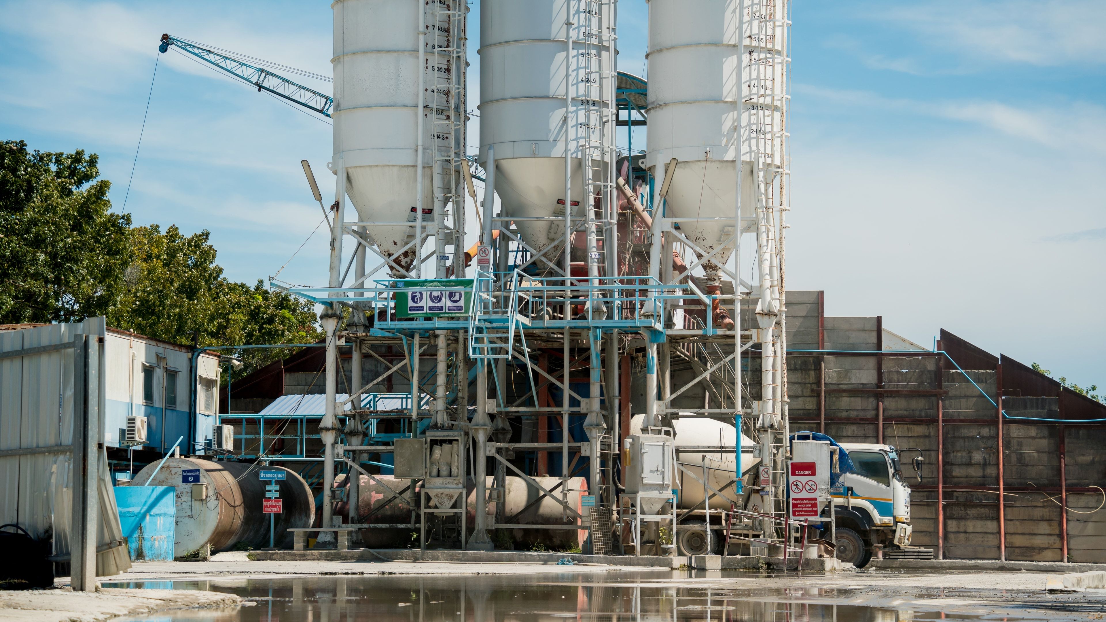 Planta de hormigón preparado con tres silos de cemento cargando un camión hormigonera